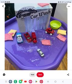 the toy cars are sitting on the purple plastic table with pink sponges and soap