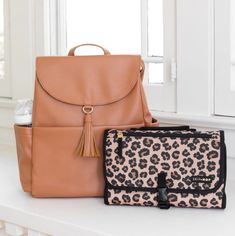 two purses sitting next to each other on top of a white counter with windows in the background