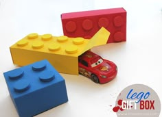 two lego blocks and a toy car are on the table next to eachother