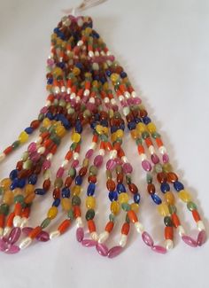 multicolored glass beaded necklace on white surface with beads hanging from it's end