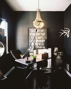 a room with black walls and a chandelier hanging from the ceiling