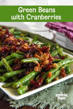 green beans with cranberries on a white plate next to a purple cloth and napkin