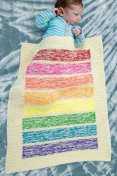 a baby laying on top of a rainbow blanket