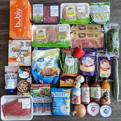 an assortment of food items laid out on a table top, including meats and vegetables