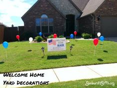 a yard decorated with red, white and blue balloons in front of a brick house