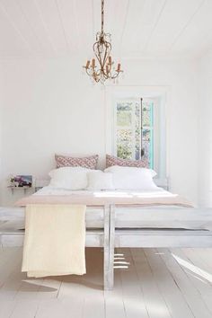 a bedroom with white walls and flooring has a bed frame made out of wood