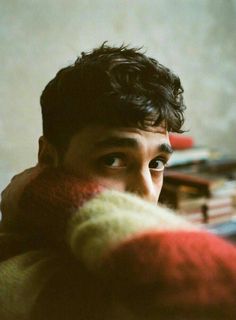 a close up of a person wearing a red and white sweater with his hand on his shoulder