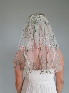 the back of a woman's wedding veil with flowers and leaves embroidered on it