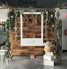 the entrance to an event with flowers and greenery hanging on it's wall