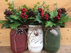 three mason jars decorated with holly and pine cones