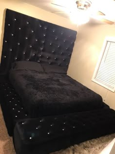 a bed with black velvet headboard and foot board in a bedroom area that has carpeted flooring