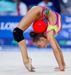 a woman bending over while holding onto a red ball