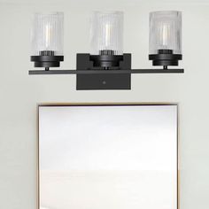 a bathroom vanity with three lights and a mirror on the wall next to it,