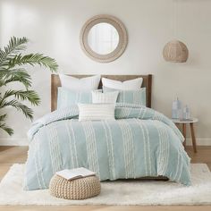 a bed with blue and white comforters in a bedroom next to a mirror on the wall