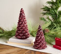 two red ceramic christmas trees sitting on top of books