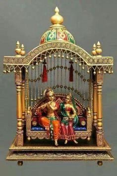 a statue of two people sitting on top of a golden bed with red and green decorations