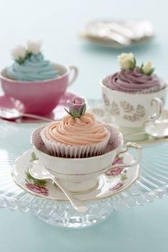 three cupcakes in teacups on a table