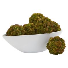 a white bowl filled with green mossballs on top of a white tablecloth covered floor