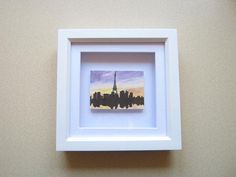 a white frame with a picture of a city skyline in it on a beige wall