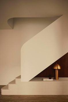 a white stair case with a gold lamp on it