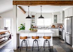 a kitchen with two stools and an island in the middle, surrounded by white cabinets