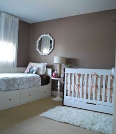 a baby's room with two white cribs and a mirror on the wall