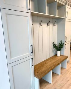 a wooden bench sitting in the middle of a room next to white cabinets and drawers