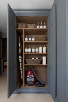 an open cabinet with many items in it and a vacuum cleaner on the bottom shelf