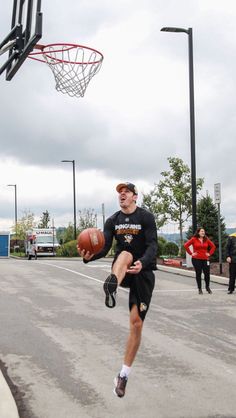 a man is jumping in the air to dunk a basketball at an outdoor court