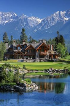 a large house sitting on top of a lush green field next to a lake and mountains