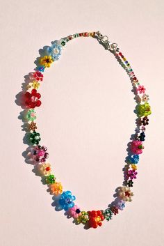 a multicolored beaded necklace is displayed on a white surface with small beads