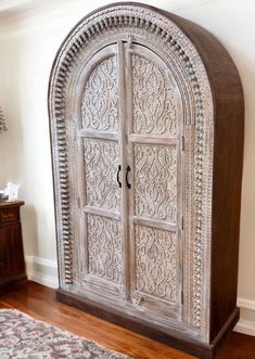 an ornate wooden cabinet in the corner of a room with a rug on the floor