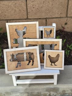 four framed pictures with farm animals on them in front of a brick wall and grass