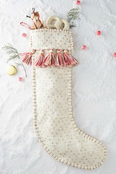 a white christmas stocking with pink trim and tassels on it's side