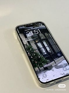 an iphone is sitting on the table with its screen partially covered in snow and trees