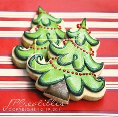 three decorated christmas tree cookies sitting on top of a table