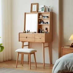 a wooden desk with a mirror and stool in front of it next to a window