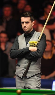 a man standing next to a pool table with a cue in his hand