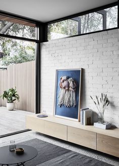 a white brick wall in a living room next to a painting on a wooden shelf