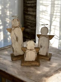 three wooden angel figurines sitting on top of a table next to each other