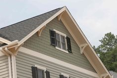 a gray house with black shutters and white trim on the windows is seen in this image