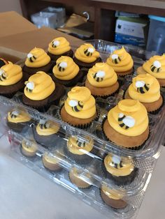 cupcakes with yellow frosting and bees on them in a plastic container sitting on a table