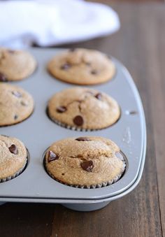 a muffin tin filled with chocolate chip cupcakes on top of a wooden table