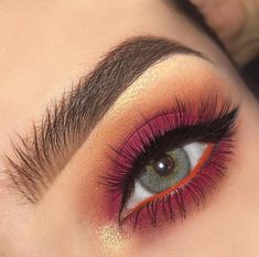 a woman's eye with bright pink and orange makeup