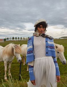 a woman standing next to two horses in a field