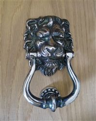 a metal lion head door handle on a wooden table with wood grained flooring