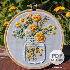 the embroidery pattern shows yellow and white flowers in a mason jar