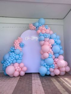 an arch made out of balloons in the middle of a room with a white wall