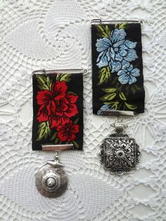 three small purses with flowers on them sitting on a lace doily next to a camera