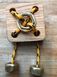 a wooden block with two metal bells attached to it's sides and rope wrapped around the block